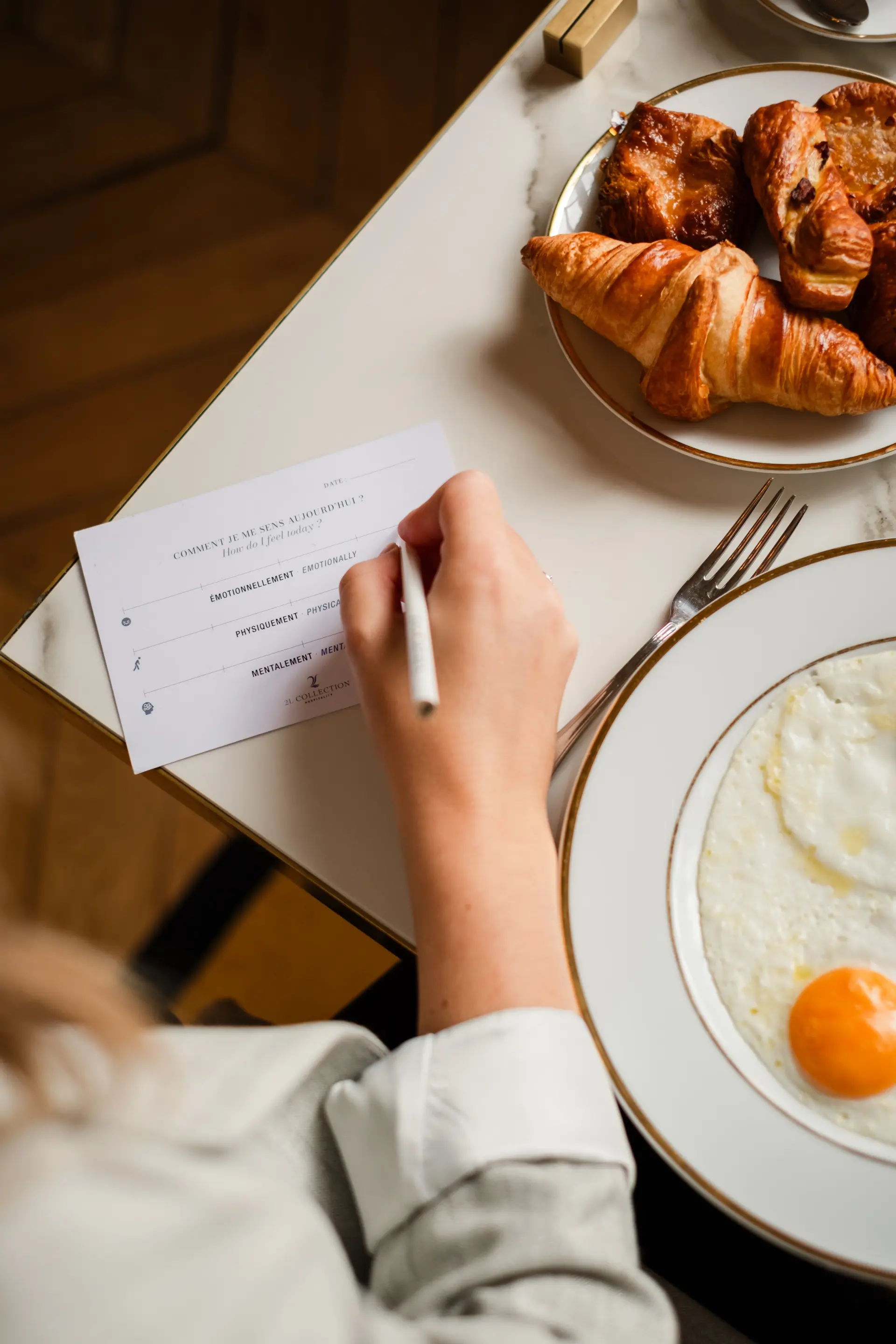 Une main qui écrit sur un papier pendant un petit déjeuner sur une table